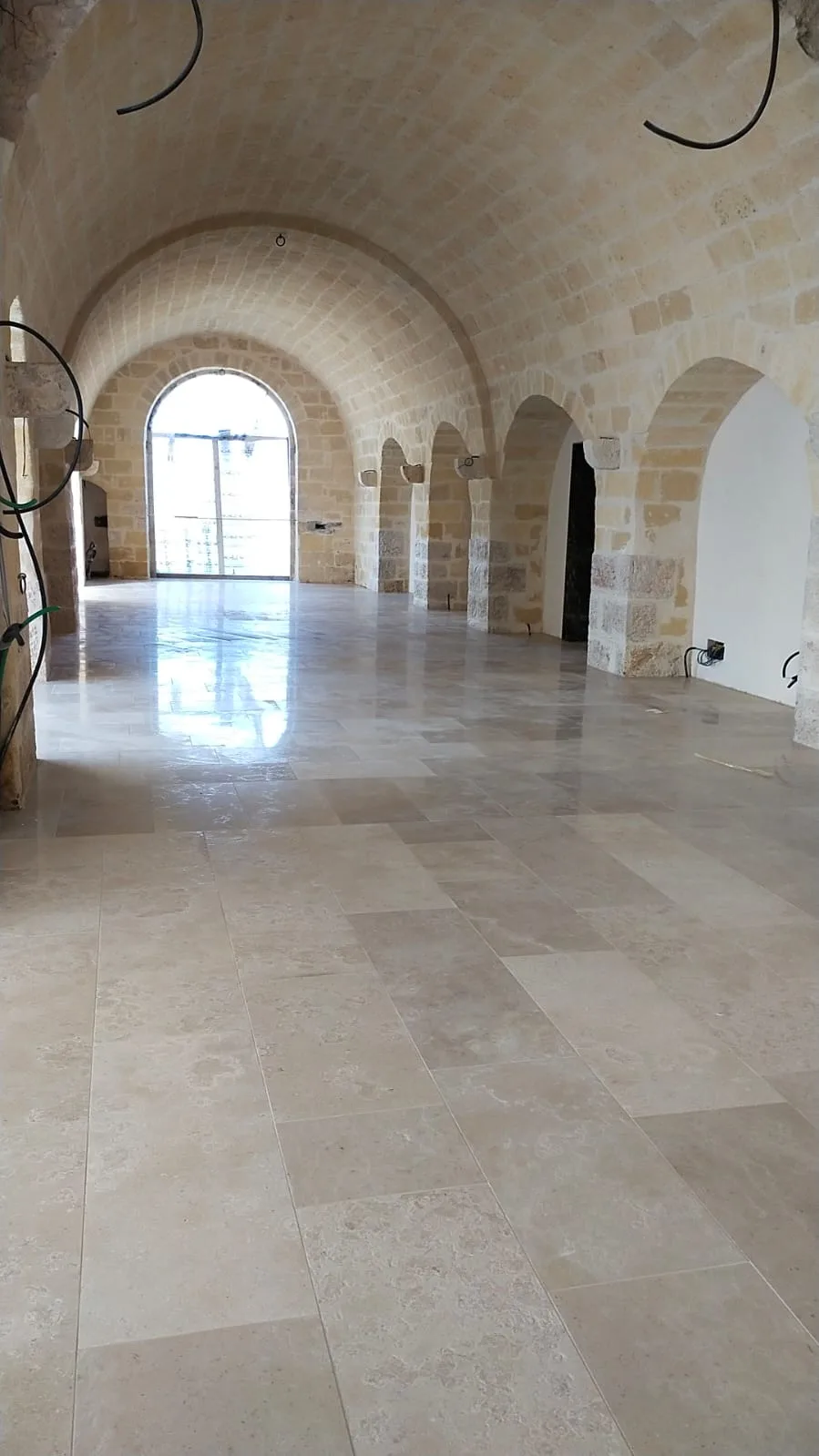 Primo piano del marmo Trani spazzolato dai toni dorati accanto a un piano in legno