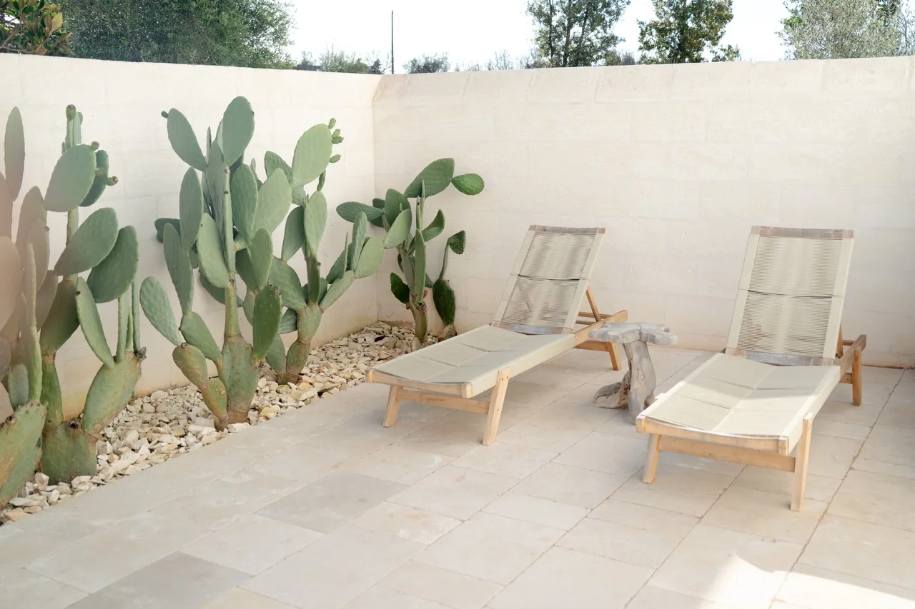 Outdoor courtyard paved in tumbled Trani marble with prickly pears and sun loungers