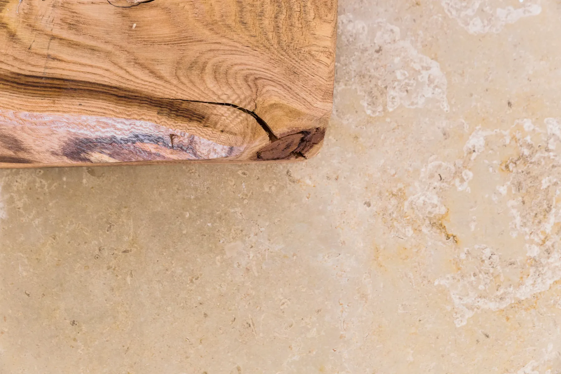 Primo piano del marmo Trani spazzolato dai toni dorati accanto a un piano in legno