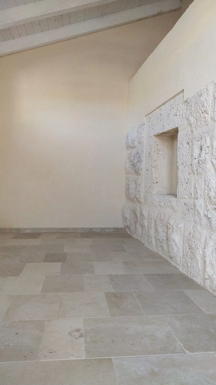 Primo piano del marmo Trani spazzolato dai toni dorati accanto a un piano in legno