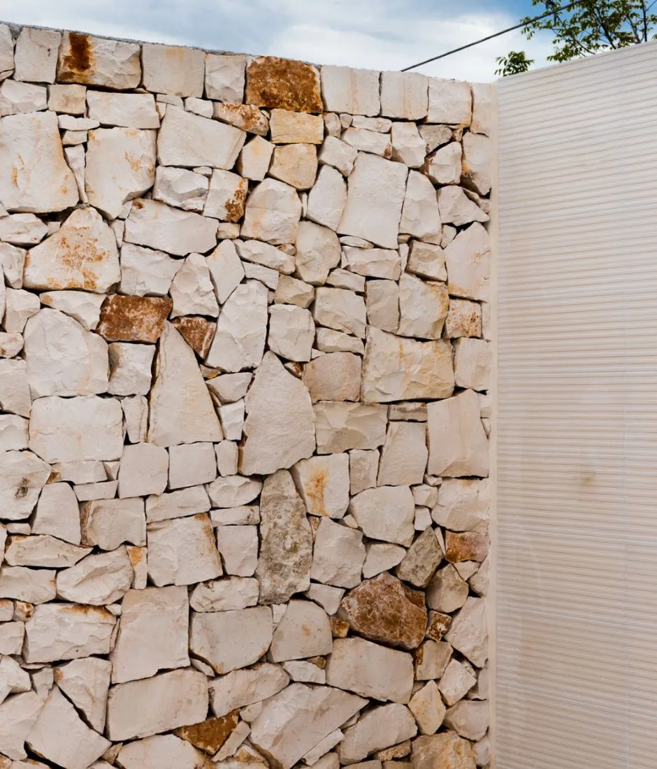 Muro in pietra a secco accostato a un rivestimento in lastre rigate chiare