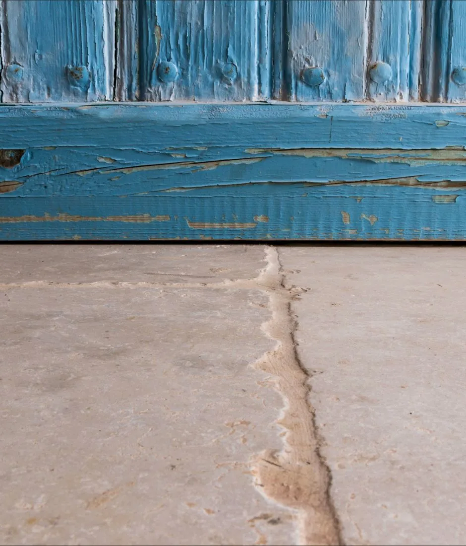 Base di una porta in legno azzurro sopra un pavimento in pietra chiara