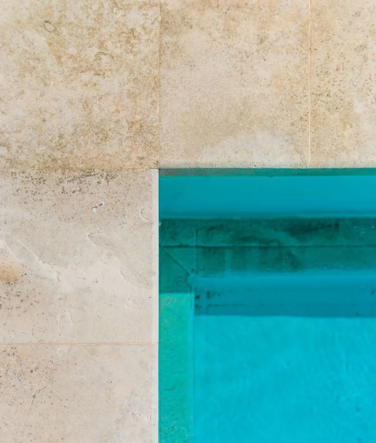 Angolo della piscina visto dall'alto, con bordo in lastre di pietra chiara
