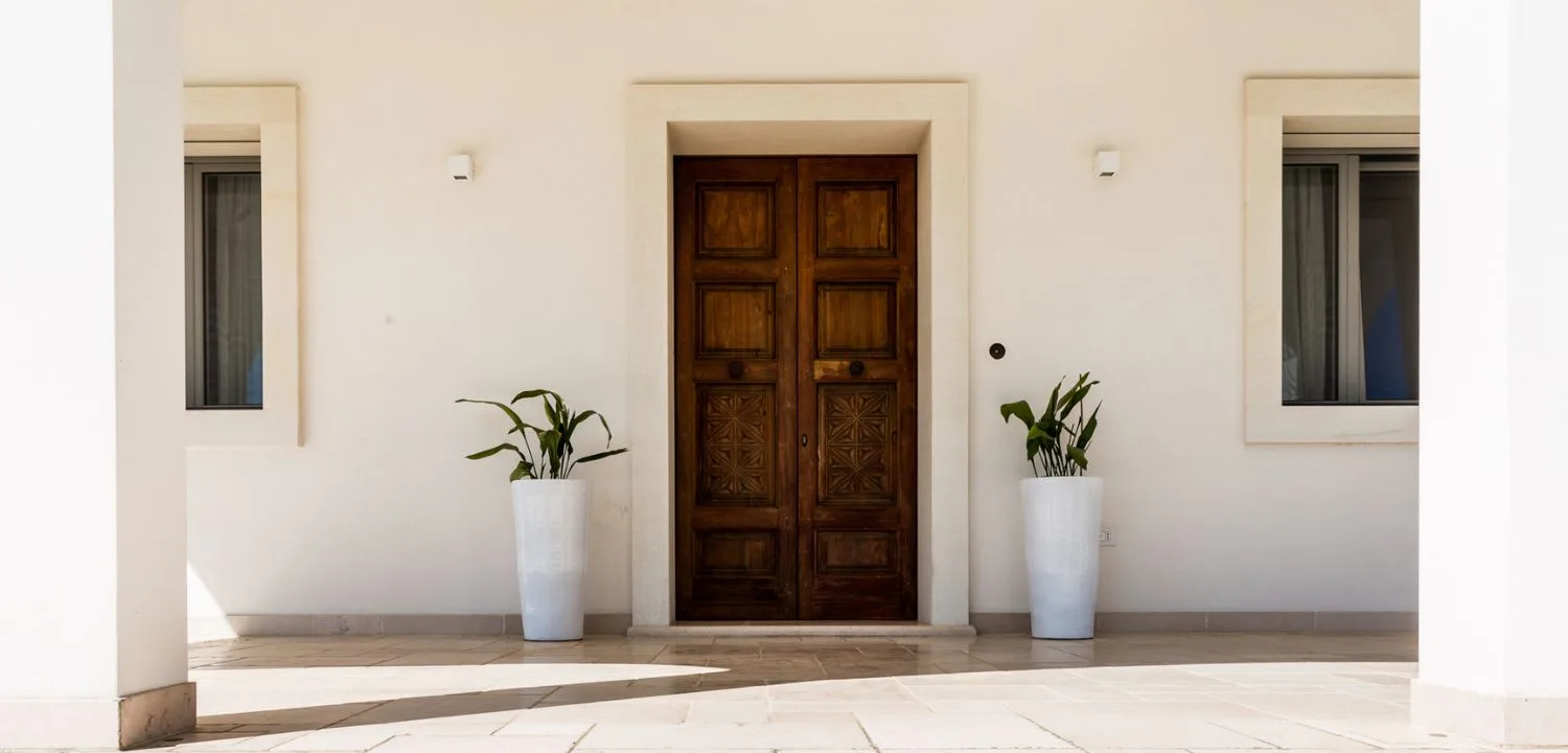 Entrance of a villa in Squinzano with a carved wooden door and paving in pale slabs