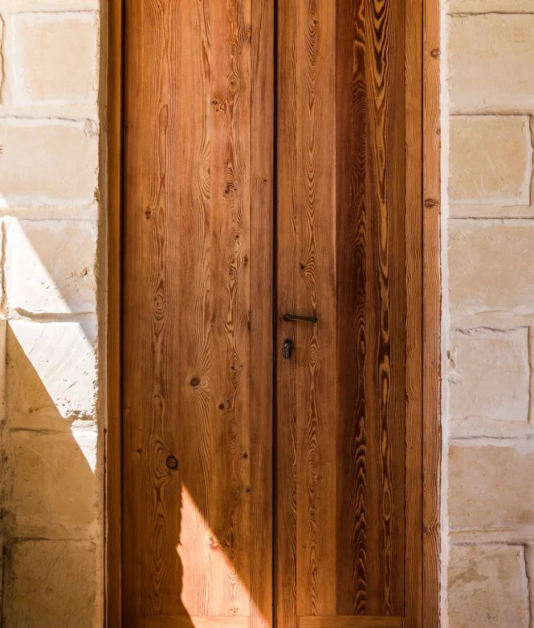 Porta in legno chiaro inserita in un muro in conci di pietra