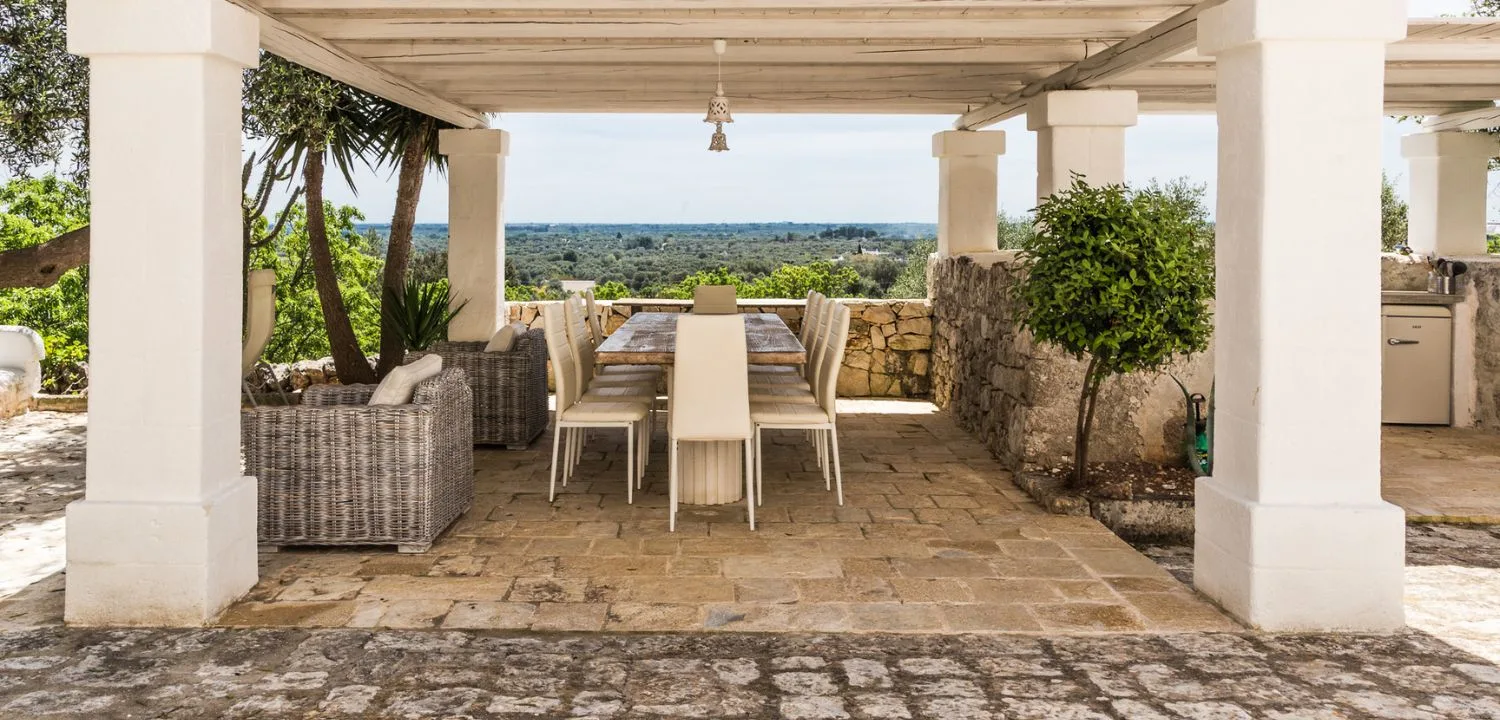 Covered terrace at Borgo Montetorto with a table, white pillars and a floor in stone slabs