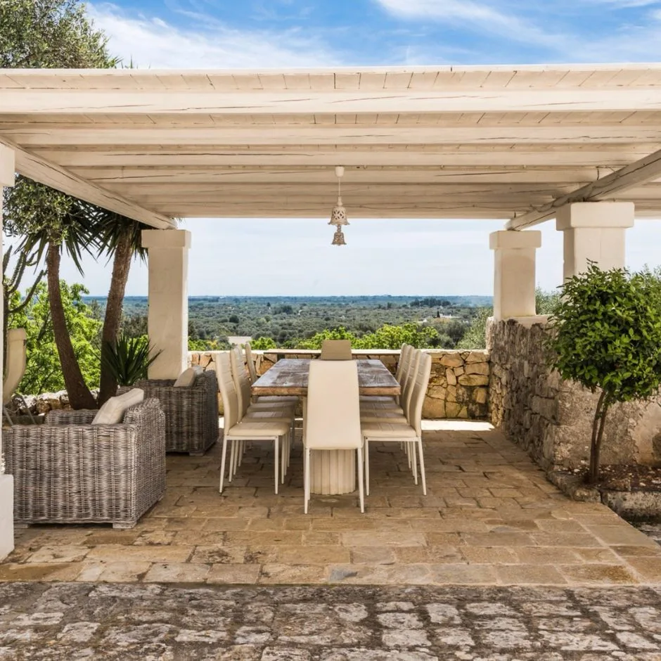 Terrazza coperta con tavolo da pranzo e vista sugli uliveti, pavimento in lastre di pietra