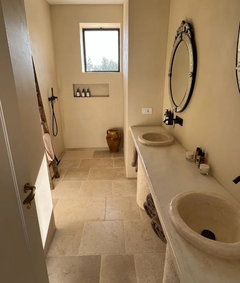 Salle de bains avec deux vasques en pierre massive, jarre en terre cuite et sol clair