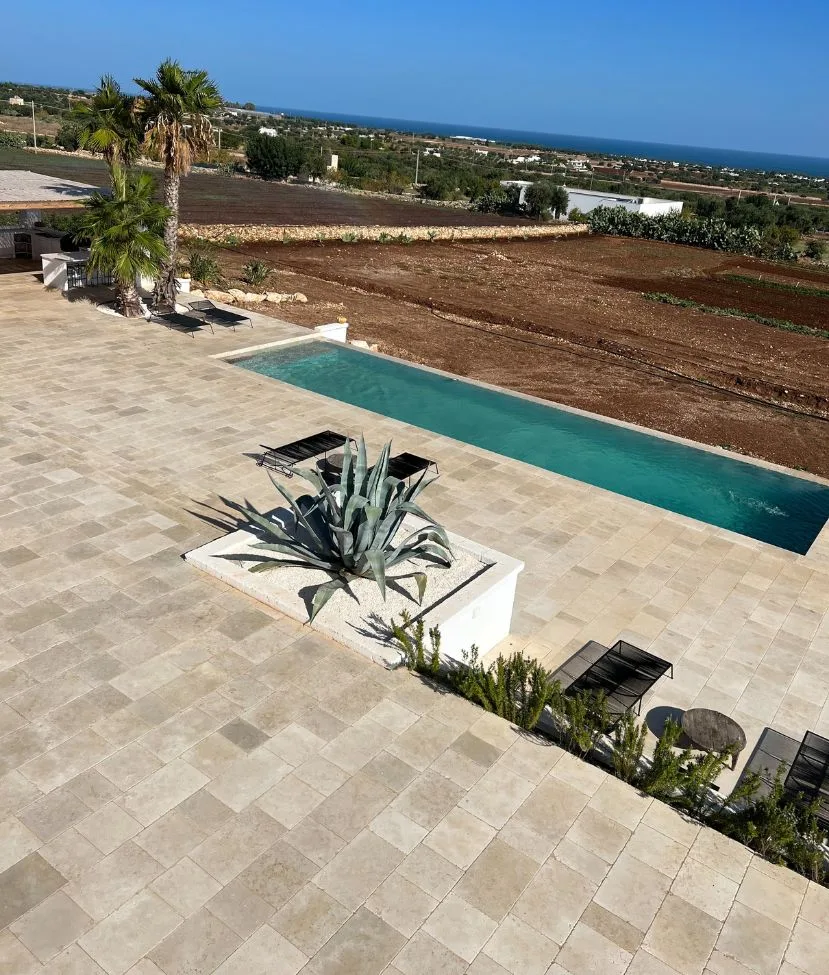 Terrasse en dalles de pierre au-dessus de la piscine, avec agave et campagne en fond