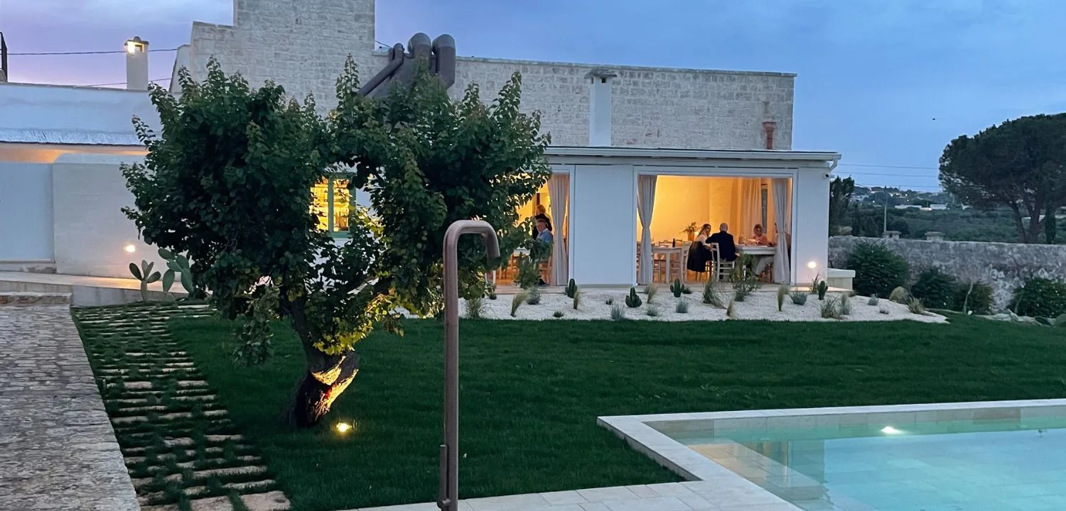 The masseria at sunset with lawn, pool and a stone walkway