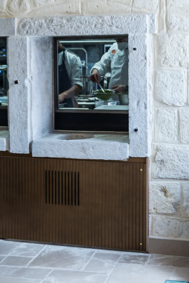Finestra passavivande verso la cucina, incorniciata in blocchi di pietra a spacco