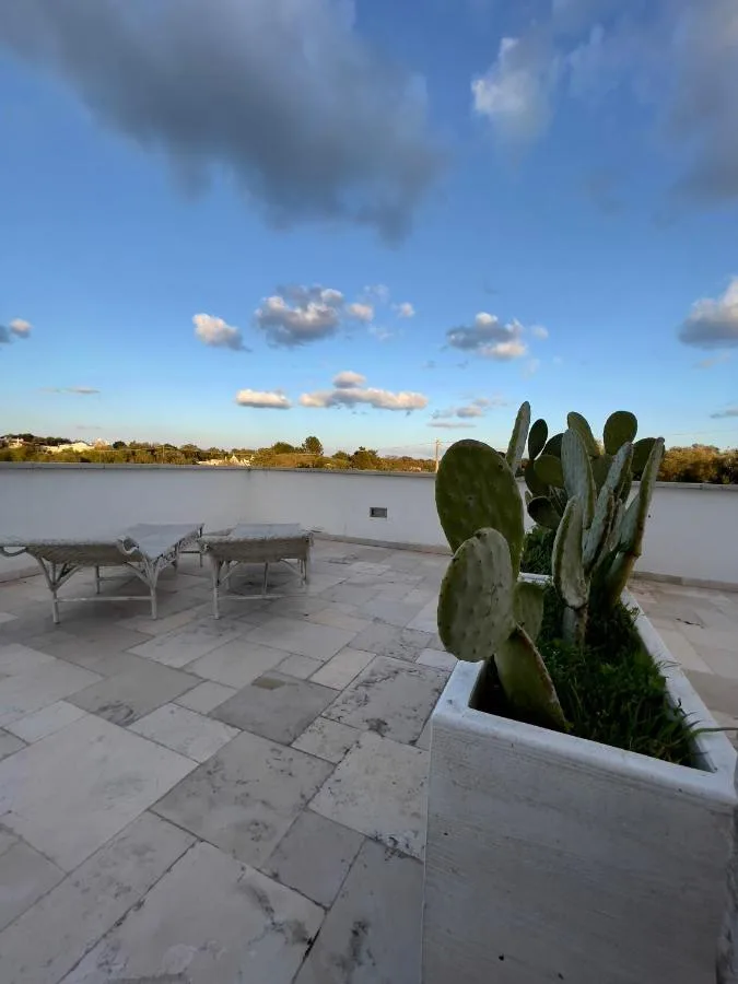 Terrace at Tenuta Ermes in Ostuni paved in pale slabs, with sun loungers and a prickly pear in a planter